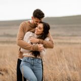Couple hugging in a field.